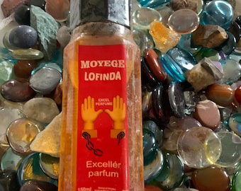 May include: A clear glass bottle with a red label that says "Moyège Lofinda Excellér parfum" and "Excel Perfume". The bottle is 150 ml and has a black cap. The label also features a cartoon image of two hands with chains.