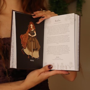 May include: An open hardcover book featuring a historical illustration of Boudica on the left page, depicted with long red hair and a sword. The right page contains biographical text titled Boudica, detailing her life and historical significance.