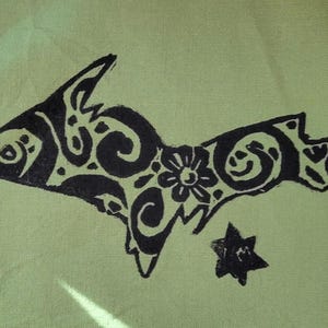 May include: A light green fabric featuring a black screen-printed graphic of the Upper Peninsula of Michigan. The map shape is filled with intricate black floral and swirling patterns, and a small black star is positioned below the map.