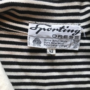 May include: A black and white striped shirt with a white collar. The shirt has a label that says "Sporting Dress" and "Reine Schur-Wolle Pure New Wool Pure Laine Vierge" with a size tag that says "42".