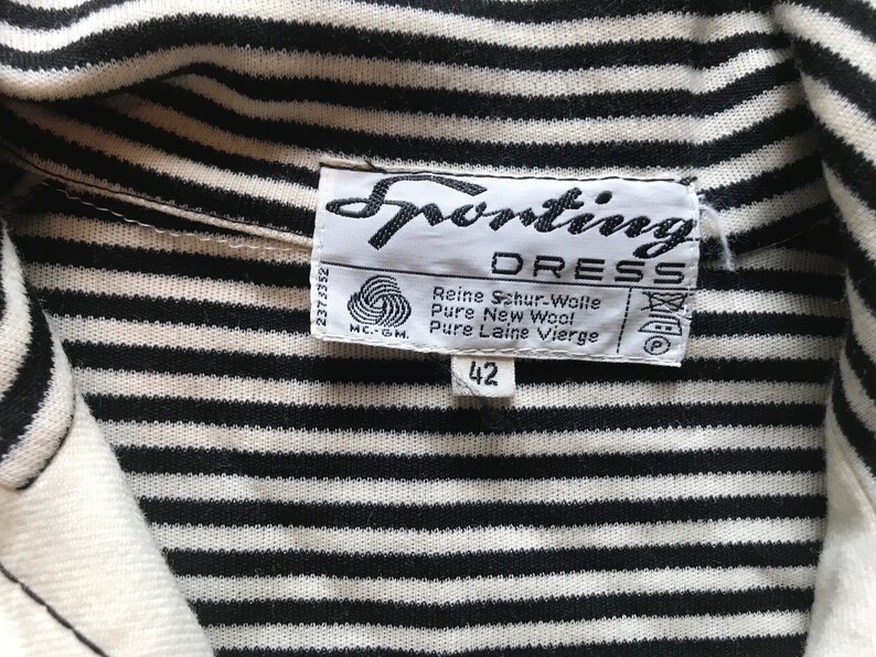 May include: A black and white striped shirt with a white collar. The shirt has a label that says "Sporting Dress" and "Reine Schur-Wolle Pure New Wool Pure Laine Vierge" with a size tag that says "42".