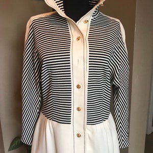 May include: A white and black striped long-sleeved dress with a white bottom half and gold buttons down the front.