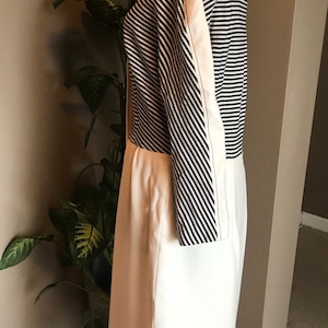 May include: A white and black striped dress with a white skirt and black and white striped sleeves. The dress has a fitted bodice and a slightly flared skirt.