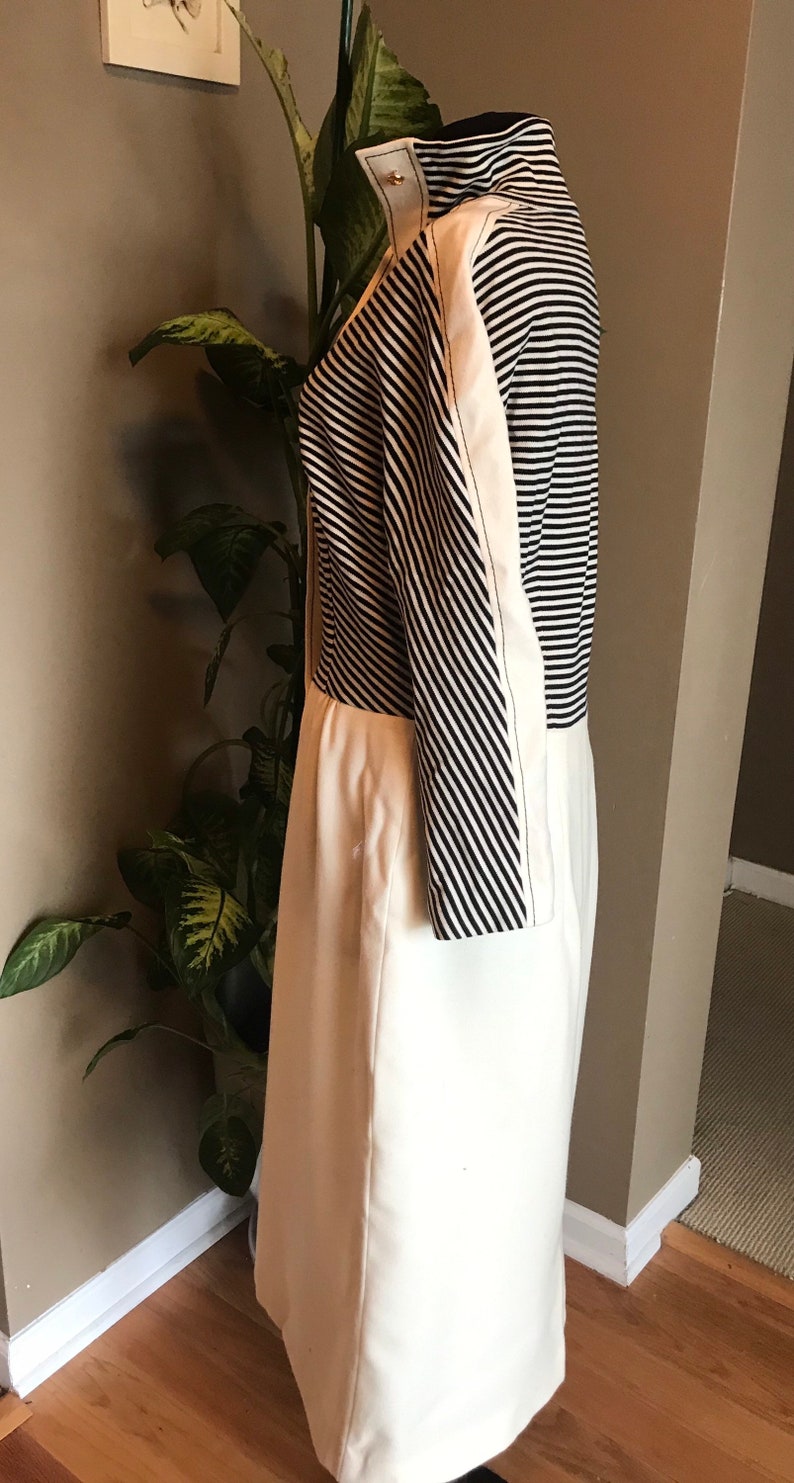 May include: A white and black striped dress with a white skirt and black and white striped sleeves. The dress has a fitted bodice and a slightly flared skirt.
