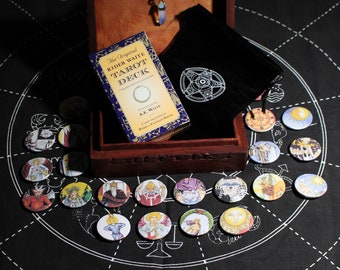 May include: A wooden box with a black velvet bag and a deck of tarot cards. The box is open and the cards are spread out on a black cloth with a white circle design. The cards are round and have colorful images on them. The text on the box reads "The Original Rider Waite Tarot Deck Compiled and Edited by A.E. Waite Cards Designed by Pamela Colman Smith."
