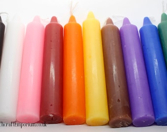 May include: Ten small, thin, taper candles in various colors, including black, white, pink, brown, orange, yellow, brown, purple, blue, and green. The candles are arranged in a row on a white surface.