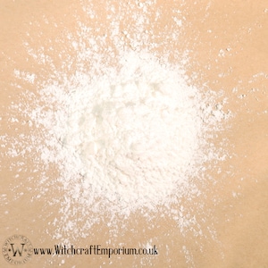 May include: A close-up of a white powder scattered on a brown surface. The powder is in a pile and has a fine texture.