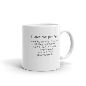 Puede incluir: Taza de café de cerámica blanca con texto negro que dice "Me encanta ir de fiesta... y por fiesta me refiero a estar en casa viendo la tele y quejándome del gobierno."