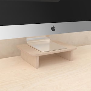 May include: A light wood monitor stand with a curved front edge. The stand is designed to elevate a computer monitor and create additional desk space.