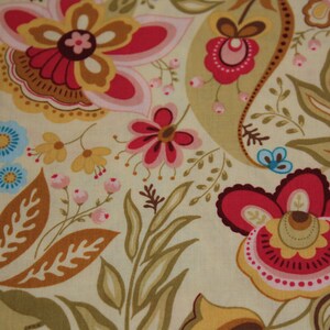 Op de afbeelding: Een beige stof met een bloemenpatroon met roze, rode en bruine bloemen. De achtergrond is lichtbeige.