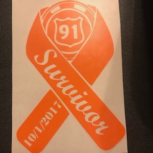 May include: Orange ribbon with the word "Survivor" written in white on it. The ribbon has a white highway sign with the number "91" on it. The date "10/1/2017" is written on the ribbon.