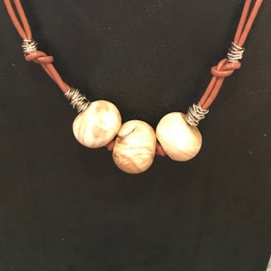 May include: A brown leather necklace with three wooden beads and silver wire accents.