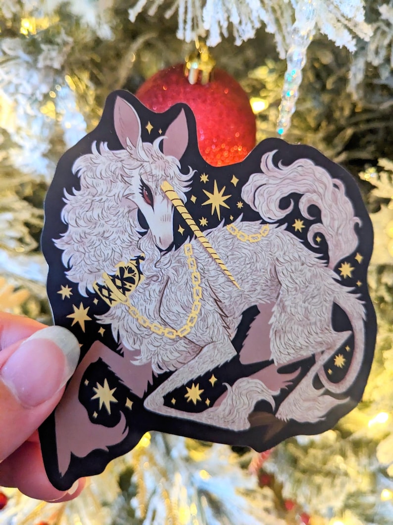 May include: A white unicorn with a gold horn and chain, surrounded by gold stars on a black background. The unicorn is depicted in a stylized, almost cartoonish style.