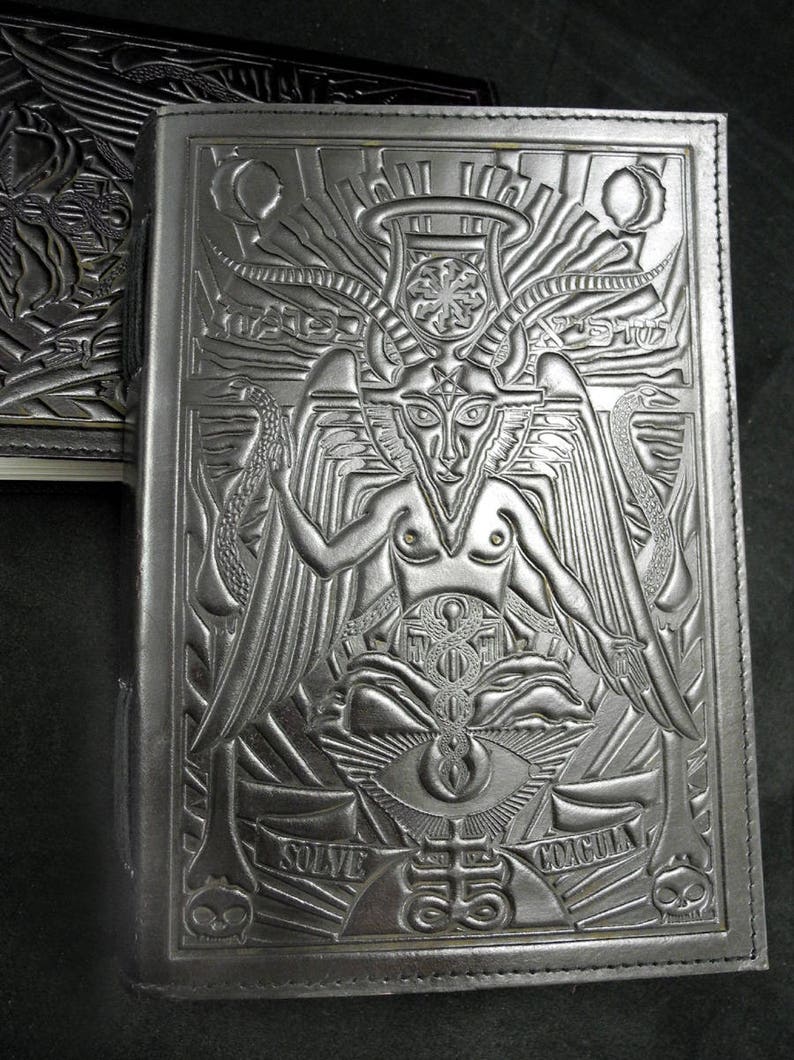 Peut inclure: Un journal reli&eacute; en cuir noir avec un motif en relief d'une figure ail&eacute;e et cornue avec un troisi&egrave;me &oelig;il. Les mots "Solve" et "Dracula" sont en relief au bas de la couverture.