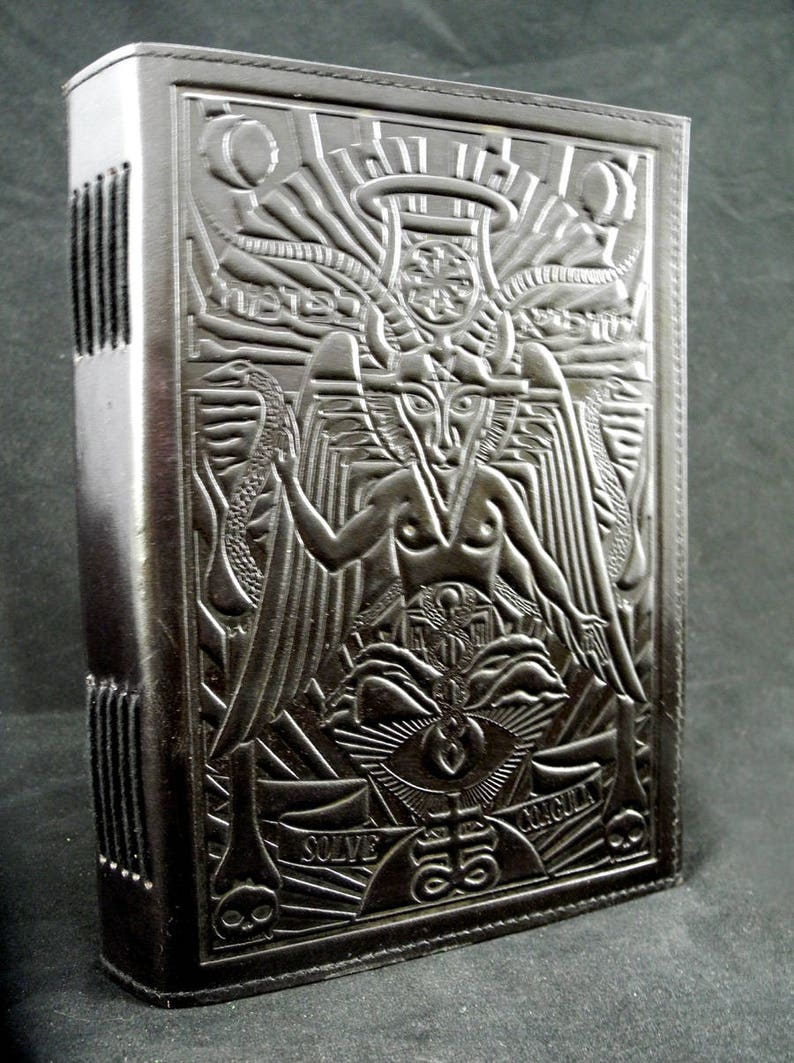 Peut inclure: Journal reli&eacute; en cuir noir avec un motif en relief repr&eacute;sentant une figure ail&eacute;e, un &oelig;il et les mots "Solve" et "Circuit".