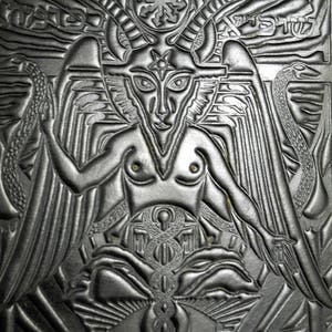 Peut inclure: Un portefeuille en cuir noir et argent emboss&eacute; avec une image d&eacute;taill&eacute;e d'une figure ail&eacute;e et cornue avec un pentagramme sur le front. La figure est entour&eacute;e de serpents et d'autres symboles.