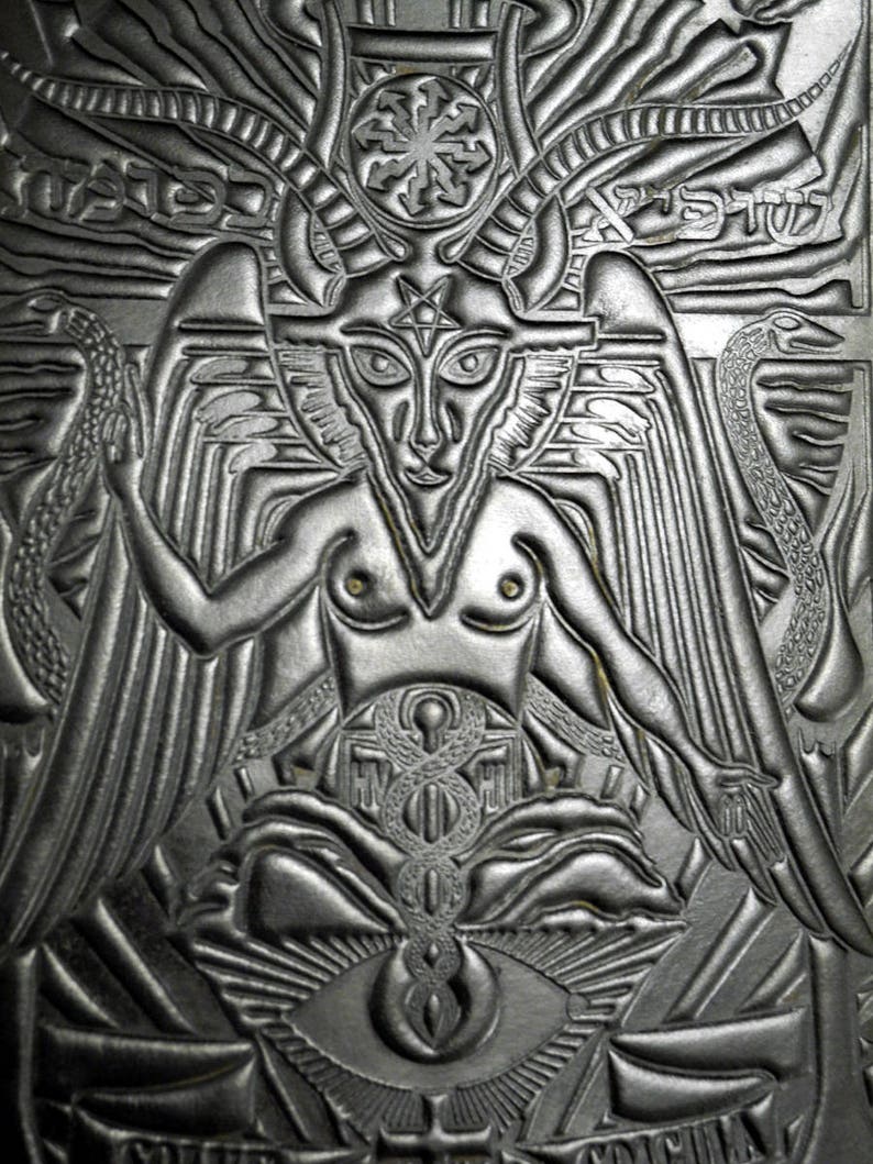 Peut inclure: Un portefeuille en cuir noir et argent emboss&eacute; avec une image d&eacute;taill&eacute;e d'une figure ail&eacute;e et cornue avec un pentagramme sur le front. La figure est entour&eacute;e de serpents et d'autres symboles.
