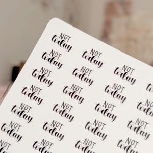 Puede incluir: Una hoja de pegatinas blanca que presenta múltiples diseños de texto negro repetidos que dicen "NOT today" en una fuente estilizada de estilo pincel. Las pegatinas están dispuestas en un patrón de cuadrícula sobre una hoja rectangular con esquinas redondeadas.