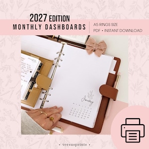 Puede incluir: Una agenda de anillas tamaño A5 abierta con un panel mensual para enero de 2027. El papel blanco muestra un calendario y dibujos florales. Una cubierta de color marrón similar al cuero sujeta las páginas, junto a un lazo y un bolígrafo.