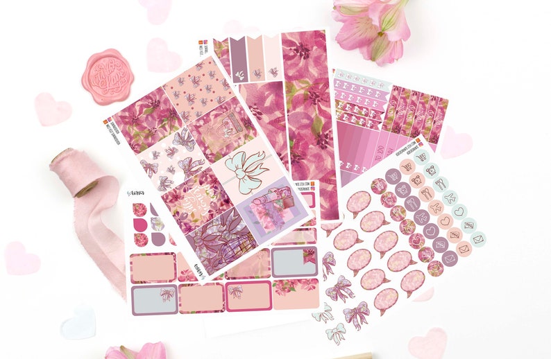 May include: A collection of planner sticker sheets featuring floral patterns in shades of pink, magenta, and cream. The set includes rectangular boxes, circular icons with symbols like envelopes and planes, and decorative bow illustrations on adhesive paper.