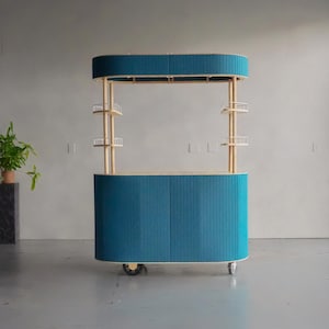May include: A teal mobile bar cart with a curved design. The cart has a teal fabric exterior with vertical lines, supported by wooden posts and small shelves. The top has a matching teal canopy. The cart is on wheels.