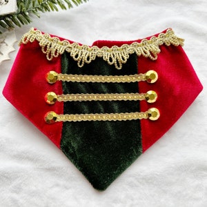 May include: Red and green velvet dog collar with gold trim and gold buttons. The collar has a festive, holiday theme.