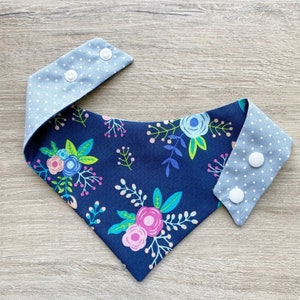 Könnte beinhalten: Ein blaues Bandana mit einem Blumenmuster und weißen Punkten auf der Rückseite. Das Bandana hat zwei weiße Druckknöpfe.