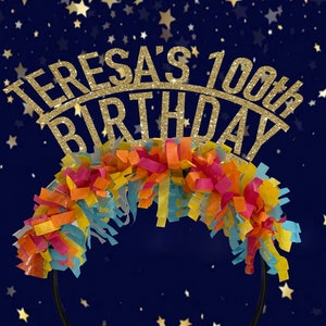May include: A black headband with a gold glitter "Teresa's 100th Birthday" sign and colorful tissue paper streamers.