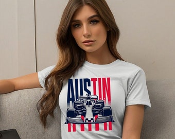 Könnte beinhalten: Weißes T-Shirt mit einem Aufdruck eines Rennwagens und dem Wort "AUSTIN". Der Wagen befindet sich vor einem rot-weiß-blauen gestreiften Hintergrund.