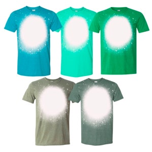 May include: Five t-shirts in different colors with a white circle spray painted on the front. The shirts are teal, green, light green, olive green, and dark green.