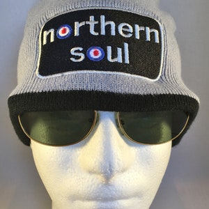 May include: Grey knitted beanie with a black and white patch that says "northern soul" with a target symbol.