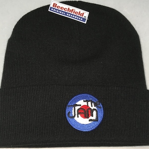 May include: Black knit beanie with a blue, white and red embroidered target logo with the text "The Jam" inside the target.