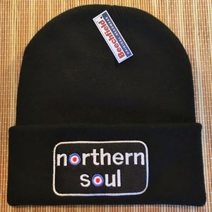May include: Black beanie with a white "northern soul" patch featuring a red, white and blue target design. The beanie is made by Beechfield.