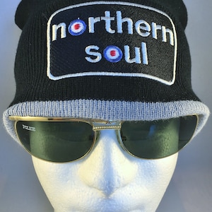 May include: Black knit beanie with a grey brim and a white embroidered patch that says "northern soul" with a red, white and blue target symbol.