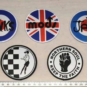 May include: Five round embroidered patches with various designs. The patches feature the text "The Kinks", "mods", "The Jam", "Northern Soul", and "Keep The Faith".
