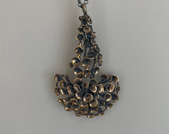 May include: A gold and silver necklace with a pendant shaped like a flower with many small petals.
