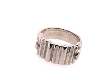 May include: A silver ring with a textured, ridged design. The ring is made of metal and has a smooth, polished finish.