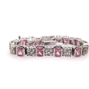 May include: A silver bracelet featuring pink and clear cubic zirconia stones. The bracelet has a square-shaped design with alternating pink and clear stones.