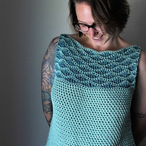 Può includere: Un top in crochet color turchese con scollo a righe. Il top è senza maniche e ha una vestibilità ampia.