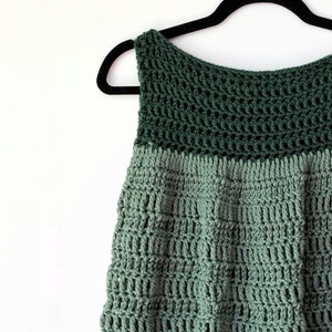 May include: A green crochet top with a sleeveless design. The top is made with a two-tone yarn, with a darker green top and a lighter green bottom.