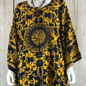 May include: A loose-fitting kaftan dress featuring a dark navy blue base with a vibrant gold-colored ornate acanthus leaf pattern. The garment includes a central circular medallion design with floral details and wide, flowing sleeves.