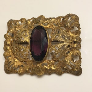 Art nouveau ornate brass brooch or belt buckle with a chipped amethyst glass in the middle circa 1900s image 1