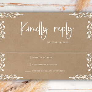 May include: A tan wedding RSVP card with white text and floral corner accents. The card reads "Kindly reply by June 10, 2023." Includes checkboxes for accepting or declining, and a line for the number of guests attending.