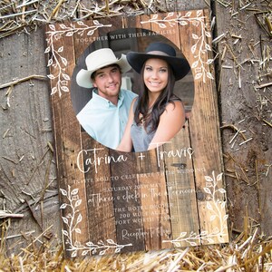 K&ouml;nnte beinhalten: Eine rustikale Hochzeitseinladung mit Holzstruktur. Die Einladung zeigt ein Foto eines Paares mit Cowboyh&uuml;ten. Der Text lautet "Catrina + Travis" und l&auml;dt die G&auml;ste ein, ihre Hochzeit am 20. Mai 2025 um 15:00 Uhr zu feiern.