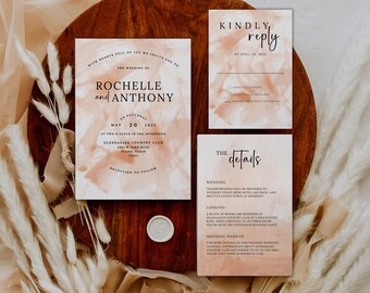 May include: Wedding invitation suite with a peach and white watercolor background. The invitation features the names Rochelle and Anthony, the date May 20, 2025, and the location Gleneagles Country Club. The RSVP card includes a section for guests to indicate their attendance and the number of guests attending. The details card provides information about the wedding, lodging, and a website for more information.