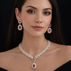 May include: A dazzling jewelry set featuring a necklace and matching earrings. The necklace and earrings showcase a vibrant red gemstone surrounded by a halo of sparkling white stones. The jewelry is set against a dark background.