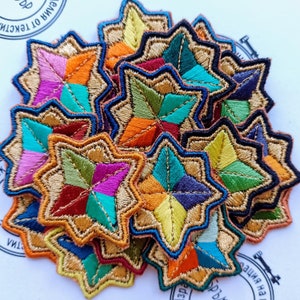 May include: A stack of colorful embroidered star-shaped patches with gold trim. The stars are made of different colored fabrics and are arranged in a random pattern.