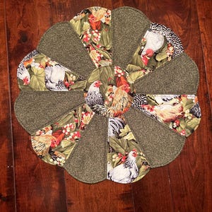 May include: A green and brown quilted table runner with a scalloped edge features a repeating pattern of chickens and berries.