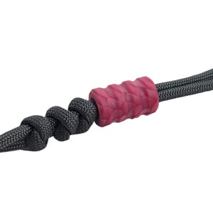 May include: A dark gray paracord lanyard with a red and black patterned bead.