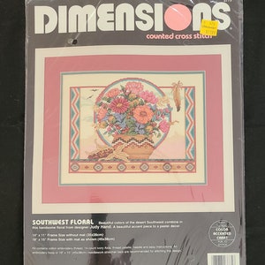 Può includere: Modello di punto croce contato Southwest Floral di Dimensions. Il disegno presenta una composizione floreale colorata in un cesto intrecciato con un bordo di design sud-occidentale. Il modello misura 14 pollici per 11 pollici e include un grafico con colori accentuati.